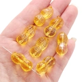 Amber-colored peanut glass beads for DIY jewelry making shown on a hand for scale - 12x23mm (Aperture 1mm) / Orange