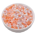 Mix of orange and pearl white glass beads and tube beads in a white bowl for DIY crafts - Persimmon Orange