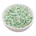 Colgantes de lirio de perlas acrílicas verde claro con aros dorados en un bol blanco - Flor de Cuatro Pétalos 7mm Verde