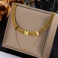 Golden mesh choker with M-letter pendant and layered chain on silk display stand - N940