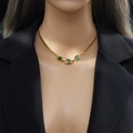 Vintage gold chain necklace with three emerald green square stones on a black blazer - Necklace