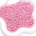 Roze pinda-vormige acryl kralen voor DIY sieraden op een wit bloemvormig blad - Dieproze