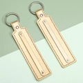 Flat rectangular light gold leather keychains with silver rings on a dual-tone background - Gold