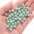 Matte mint green acrylic round beads for DIY jewelry making held in a person's palm - Sage Grey