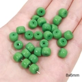 Vibrant green 8x6mm cylindrical glass spacer beads held in hand for size comparison - Solid Column Beads 8x6mm Hole 1mm Grass Green 20/Pack