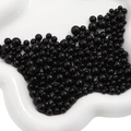 Polished black ABS faux pearls in various sizes on a white ceramic tray for DIY projects - 3-8mm / Black