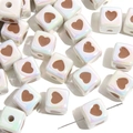 Macro shot of colorful acrylic cube beads with brown hearts and pre-drilled holes - White Cube Coffee Heart