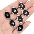 Oval black enamel tulip flower charm in silver alloy frame held in hand for scale - Oval Tulip / Black and Silver