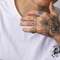 Nahaufnahme eines breit vergoldeten Edelstahlrings mit Wellenstruktur an einem Finger - US 7 / Gold