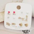 Dettaglio di un set di 6 paia di orecchini a lobo dorati con cuori, perle e scritte love - Stile 1 (Cuore Rosa)