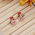 Detailed close-up of purple enamel daisy earrings with green leaves and zircon stones - Pink