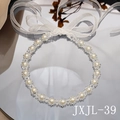 Dettaglio della fascia di perle con fiocco in nastro d'organza bianco su superficie a specchio - Stile Cristallo Perla (JXJL-39)