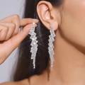 Close-up of silver tassel earrings with shimmering crystals for elegant evening wear - Silver Lightning Zigzag Tassel Earrings
