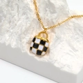 Chic gold necklace featuring a black and white checkerboard handbag pendant on white stone - Gold