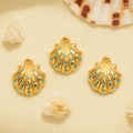 Macro detail of three golden seashell pendants with blue enamel dots for DIY jewelry making - Blue Polka Dot Shell Style