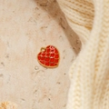 Macro detail of red enamel heart charm with golden fish scale pattern and metal loop - Red