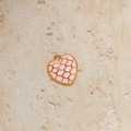 Detailed macro view of heart-shaped pendant with pink enamel and gold scales pattern - Pink