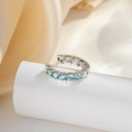 Silver huggie earring with light blue and clear zircons on a white pedestal display - Light Sea Blue (1 Pc)