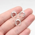 Three silver western horseshoe alloy pendants on fingertips for size comparison - Antique Silver