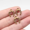 Three bronze horseshoe pendants on hand showing size and vintage metal texture details - Antique Bronze