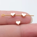 Golden heart-shaped zinc alloy beads shown on a finger to display small scale - KC Gold