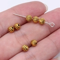 Golden pumpkin beads and silver metal pin held in hand for DIY jewelry making supplies - Pumpkin Bead Style (D10637) / Antique Gold
