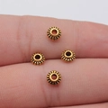 Vintage gold gear-shaped alloy spacer beads on finger for DIY jewelry making projects - Antique Gold