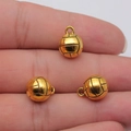 Three golden volleyball charms for DIY jewelry making shown in hand for size context - Antique Gold