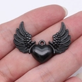 Ciondolo gotico con cuore nero e ali in lega tenuto in mano per la scala - Ali di Cuore (D11812_36x27mm)