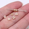 Miniature gold geometric zinc alloy spacer beads and metal pin held for scale - KC Gold