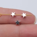 Small silver star-shaped spacer bead for jewelry making shown on finger for scale - Antique Silver