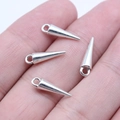 Polished silver spike cone charms for DIY jewelry making shown on fingertips for size - Antique Silver