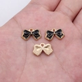 Three tiny black enamel bow pendants in gold finish resting on a hand for scale - Black (D20056_U01-A56)