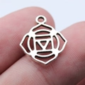 Silver 7 Chakra yoga pendant on a finger to show its miniature 15x18mm scale - Root Chakra Muladhara Symbol Style (B16863_W08-I32)
