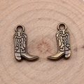 Pair of vintage bronze cowboy boot pendants with wavy textures on a wood background - Antique Bronze