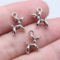 Three tiny antique silver balloon dog charms held in hand to show the miniature scale - Antique Silver