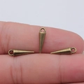 Three bronze cone pendants for DIY jewelry making shown against a finger for scale - Antique Bronze