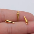 Three golden 4x16mm cone pendants for DIY jewelry making shown on a fingertip - Antique Gold