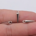 Three silver-plated spike charms for DIY jewelry making shown on a fingertip for scale - White Gold