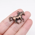Vintage bronze alloy horse pendant charm for jewelry making shown on finger - Ancient Red Copper (D11643)