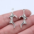 Vintage silver alloy bat wing pendants shown held between fingers for size reference - Antique Silver