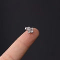 Nahaufnahme eines silbernen 16g Stahl-Helix-Steckers mit vier Zirkonia auf der Fingerspitze - 1.2x6mm / Nr. 3 Silber