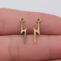Bronze lightning bolt charms held on fingertips showing miniature size for DIY jewelry - Ancient Bronze