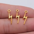 Three small gold alloy lightning bolt pendants held on finger for DIY jewelry accessories - Antique Gold