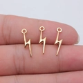Three golden lightning bolt alloy charms for DIY jewelry making shown on fingertips - KC Gold
