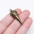 Detailed antique bronze skull bird beak pendant with ornate engraved scroll patterns - Antique Bronze