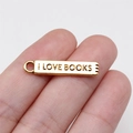 Golden rectangular I LOVE BOOKS metal pendant charm held between fingers for DIY jewelry - Antique Gold