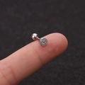 Macro-opname van een roestvrijstalen oorknopje met glanzende zirkonia op een vinger - Ronde Dichte Inlegstijl (HSPJ1915-3#)