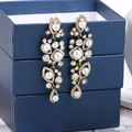 Detailed close-up of golden tassel earrings with white pearls and sparkling rhinestones - White Antique Gold