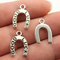 Three silver horseshoe pendants with GOOD LUCK engraving held in hand for jewelry DIY - Antique Silver